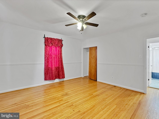 empty room with baseboards, wood-type flooring, and a ceiling fan