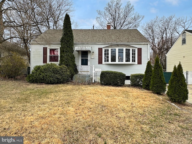 bungalow-style home with a front yard, roof with shingles, and a chimney