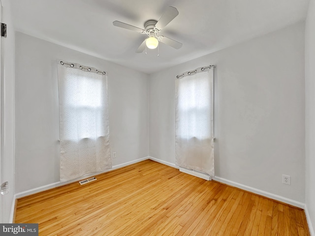 spare room featuring hardwood / wood-style floors, plenty of natural light, a ceiling fan, and visible vents