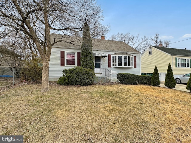 bungalow-style home with a shingled roof, a chimney, a front lawn, and fence