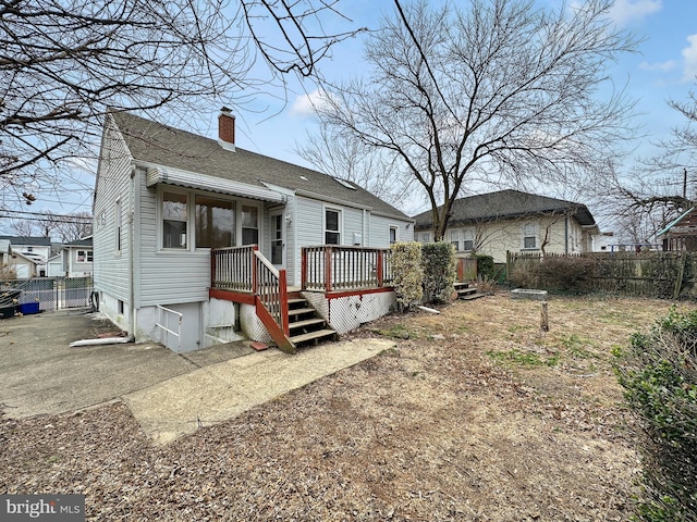 back of property featuring roof with shingles, a deck, a chimney, and fence