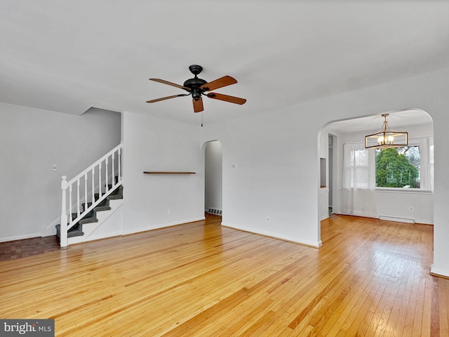 unfurnished living room with hardwood / wood-style flooring, stairway, arched walkways, and a baseboard radiator