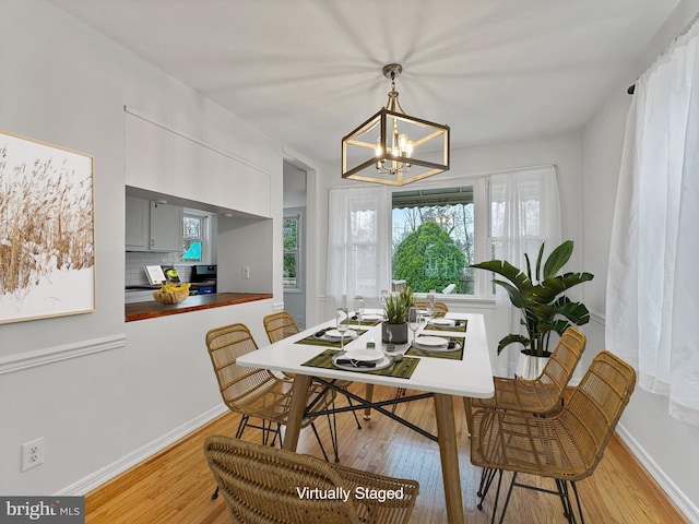 dining room with light wood finished floors, baseboards, and an inviting chandelier