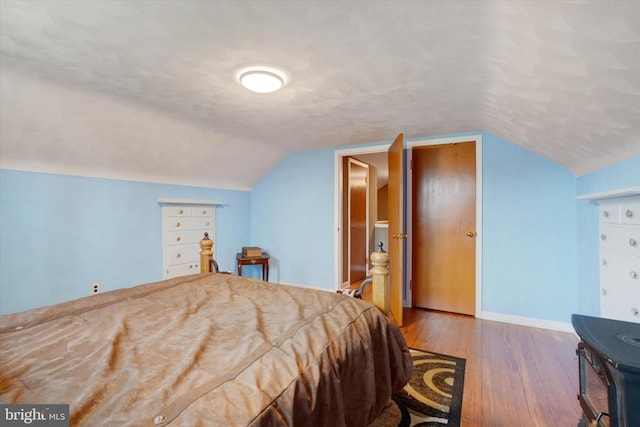 bedroom featuring hardwood / wood-style floors, lofted ceiling, baseboards, and a textured ceiling