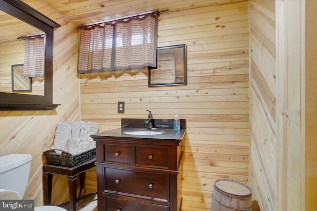 half bath with wood walls, wooden ceiling, vanity, and toilet