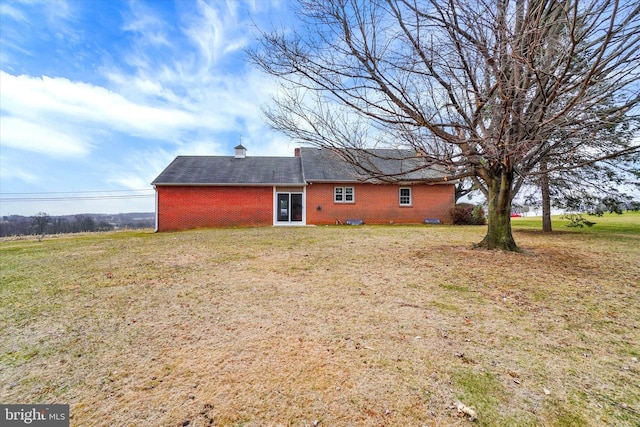 rear view of house featuring a yard and brick siding