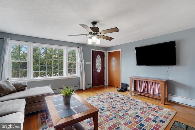 living area featuring light wood finished floors, a healthy amount of sunlight, and ceiling fan