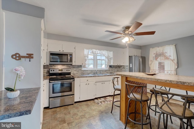 kitchen featuring white cabinetry, tasteful backsplash, appliances with stainless steel finishes, and a sink