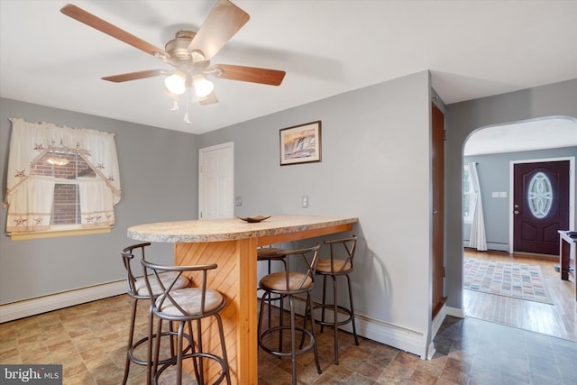 dining area featuring arched walkways, a healthy amount of sunlight, baseboards, and a ceiling fan