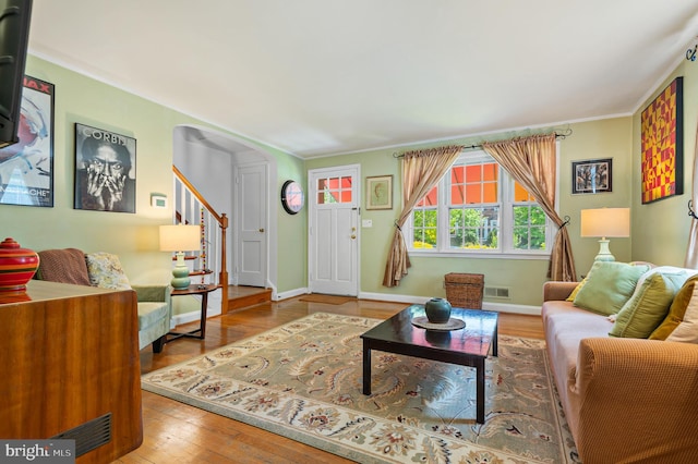 living area with baseboards, ornamental molding, wood-type flooring, and visible vents