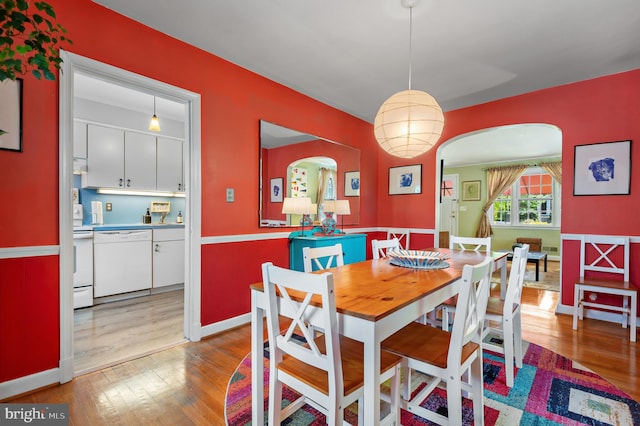 dining space with arched walkways and wood finished floors