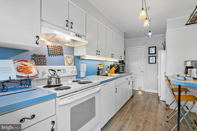 kitchen with crown molding, a sink, light countertops, under cabinet range hood, and white appliances