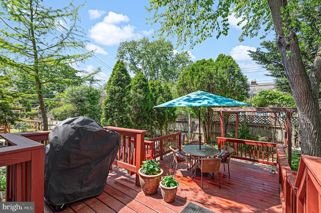 wooden deck with a fenced backyard, outdoor dining area, and a grill