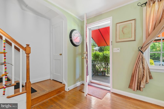 entrance foyer featuring baseboards, ornamental molding, wood finished floors, and stairway