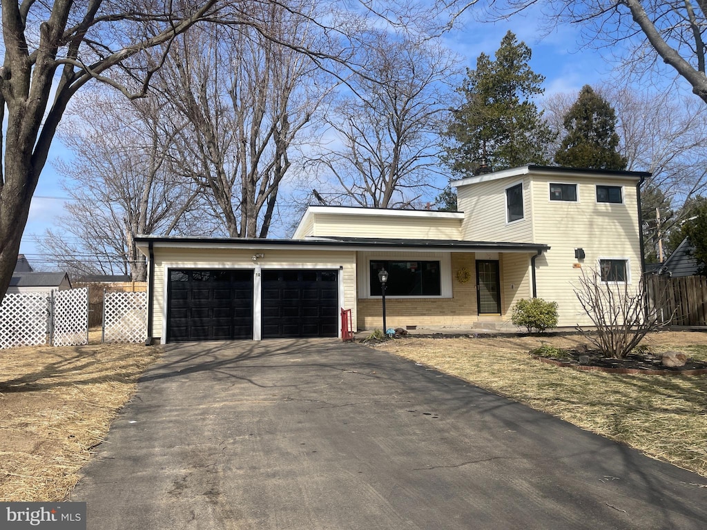 view of front facade with brick siding, fence, a garage, and driveway