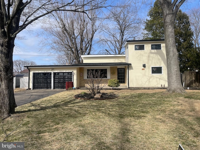 view of front of house featuring aphalt driveway, a front yard, an attached garage, and fence