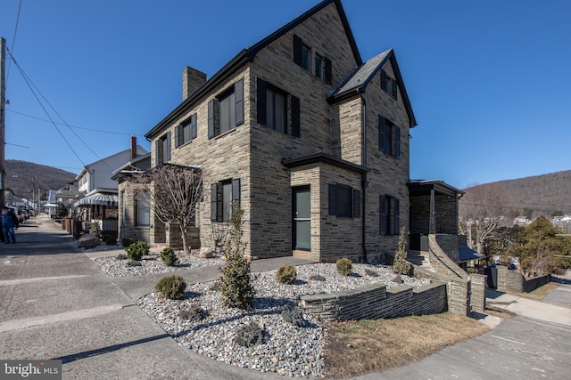 view of front of property with stone siding and a chimney