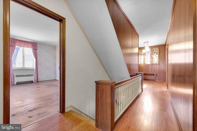 hallway with a notable chandelier, radiator, and wood-type flooring