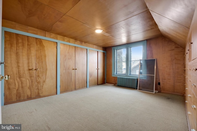 bonus room featuring wooden walls, radiator heating unit, lofted ceiling, and carpet floors