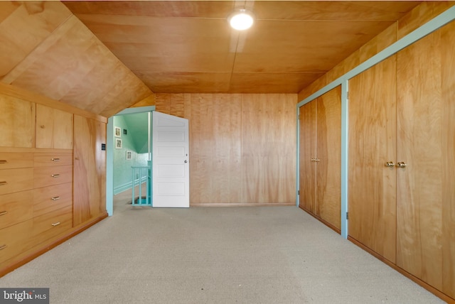 additional living space with carpet flooring, wood walls, and vaulted ceiling