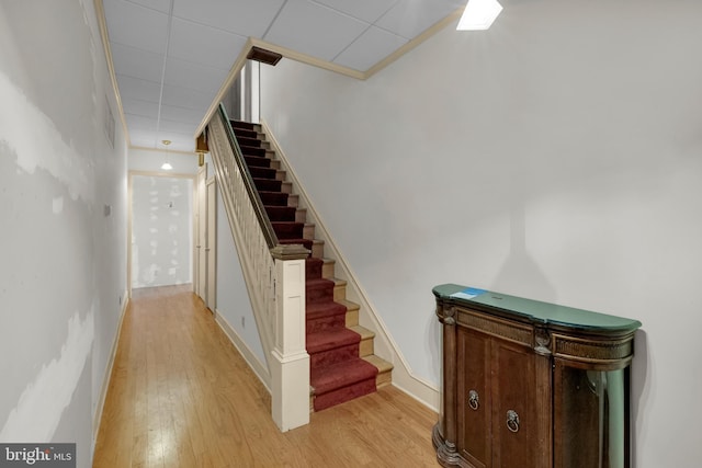 staircase featuring a drop ceiling, baseboards, and wood finished floors