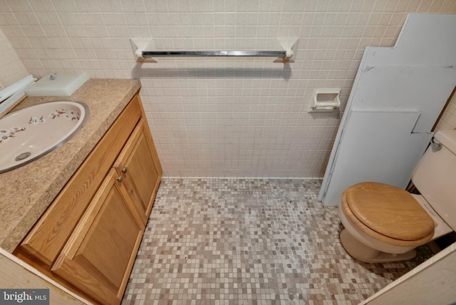 bathroom with vanity, tile walls, and toilet