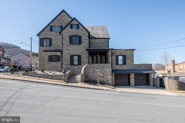 view of front of house featuring concrete driveway, a garage, and stone siding