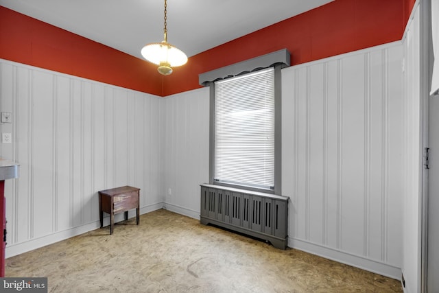 empty room featuring a decorative wall and radiator heating unit