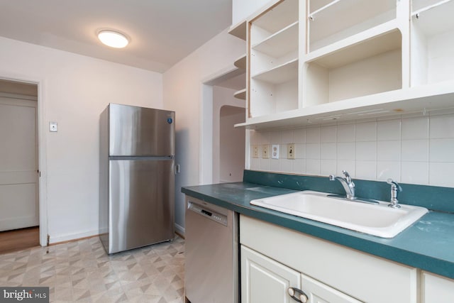 kitchen featuring a sink, open shelves, tasteful backsplash, stainless steel appliances, and light floors