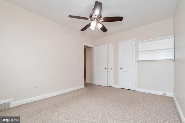 unfurnished bedroom with visible vents, two closets, carpet floors, baseboards, and ceiling fan