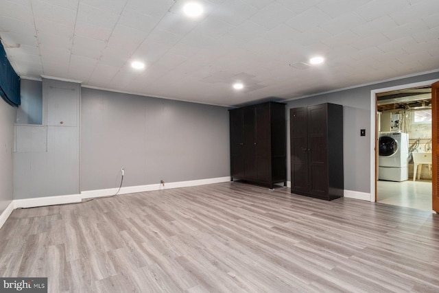 finished basement featuring light wood finished floors, washer / clothes dryer, crown molding, and baseboards