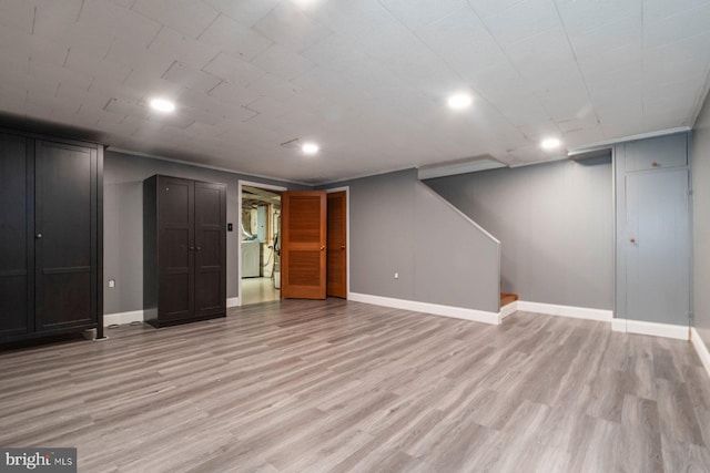 finished basement featuring stairway, baseboards, and light wood finished floors