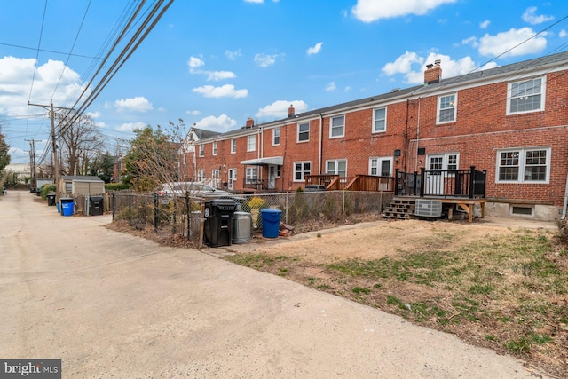 exterior space featuring brick siding, a chimney, and fence