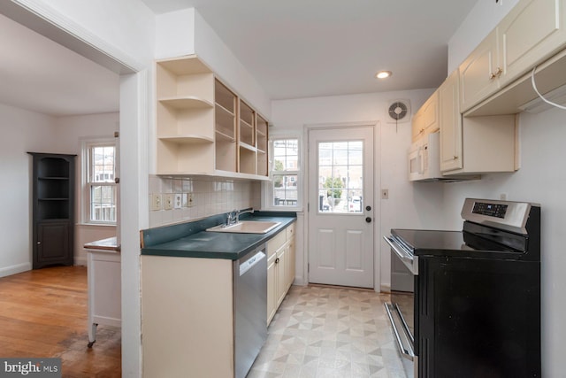 kitchen with a sink, stainless steel appliances, dark countertops, and a wealth of natural light