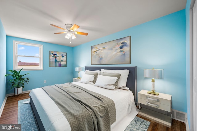 bedroom featuring a ceiling fan, wood finished floors, visible vents, and baseboards