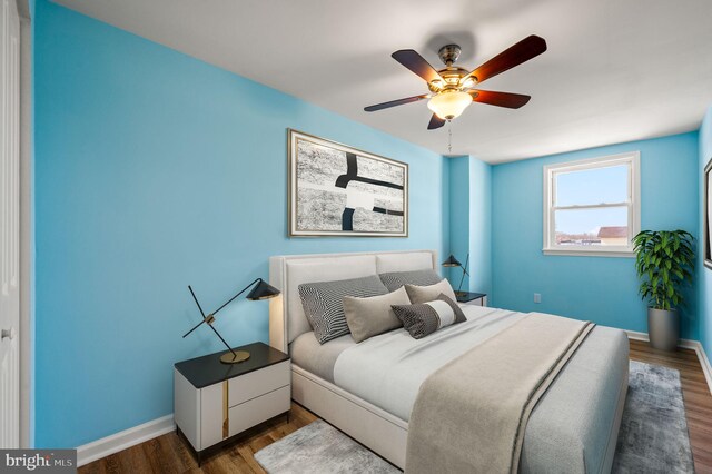 bedroom with a ceiling fan, baseboards, and wood finished floors