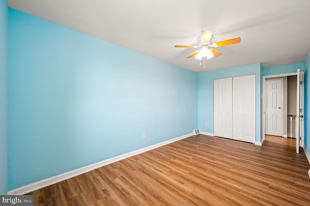 unfurnished bedroom featuring a closet, ceiling fan, baseboards, and wood finished floors