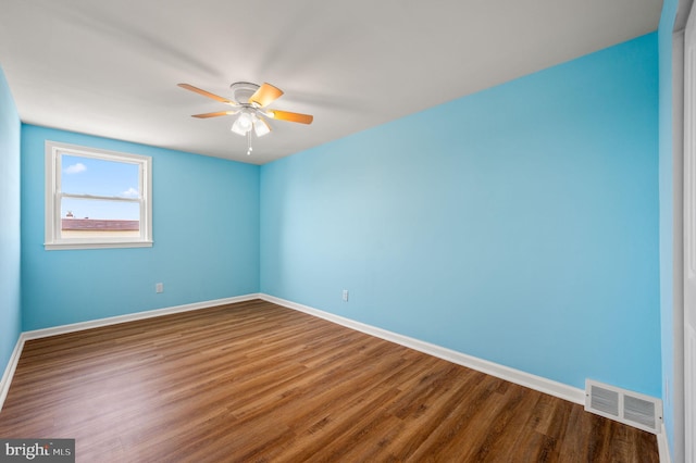 empty room with ceiling fan, wood finished floors, visible vents, and baseboards