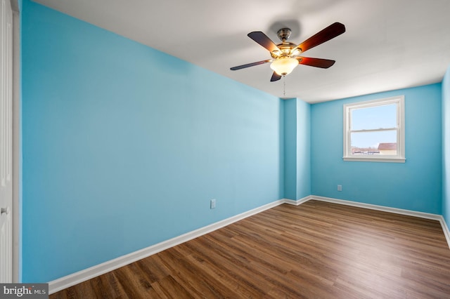 empty room with ceiling fan, baseboards, and dark wood-style floors