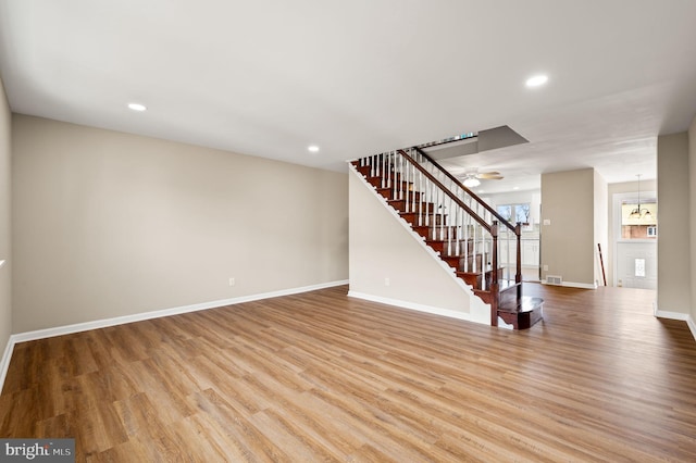 unfurnished living room featuring recessed lighting, baseboards, wood finished floors, and stairs