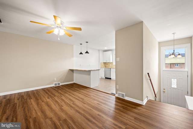 unfurnished living room with wood finished floors, visible vents, and baseboards