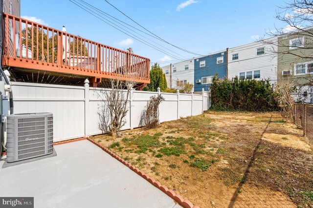 view of yard with a deck, a patio, central air condition unit, and a fenced backyard