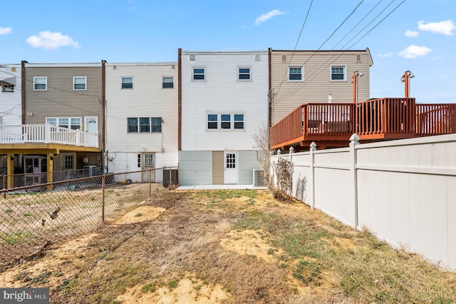 rear view of property featuring a wooden deck, central AC unit, and fence