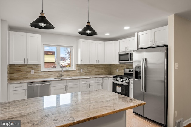 kitchen featuring white cabinets, backsplash, appliances with stainless steel finishes, and a sink