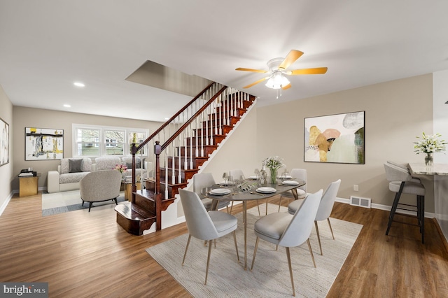 dining area featuring visible vents, stairs, baseboards, and wood finished floors