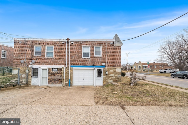 view of front of home featuring brick siding, an attached garage, fence, stone siding, and driveway