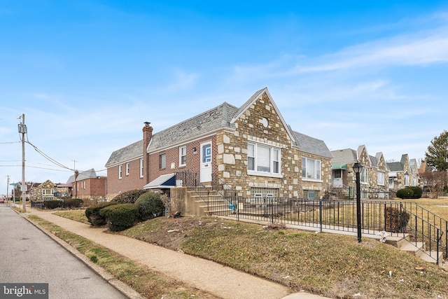 view of front facade with stone siding, a residential view, and fence