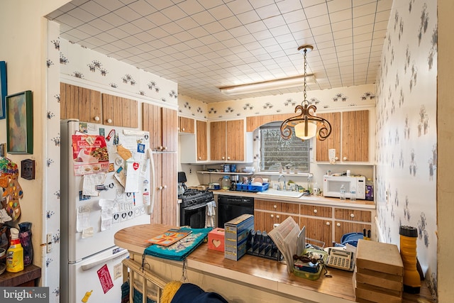 kitchen featuring light countertops, brown cabinets, hanging light fixtures, black appliances, and a sink