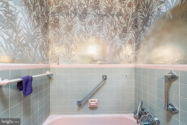 full bathroom featuring a bathing tub, wainscoting, and wallpapered walls