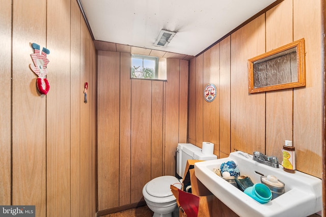 half bath with wooden walls and toilet